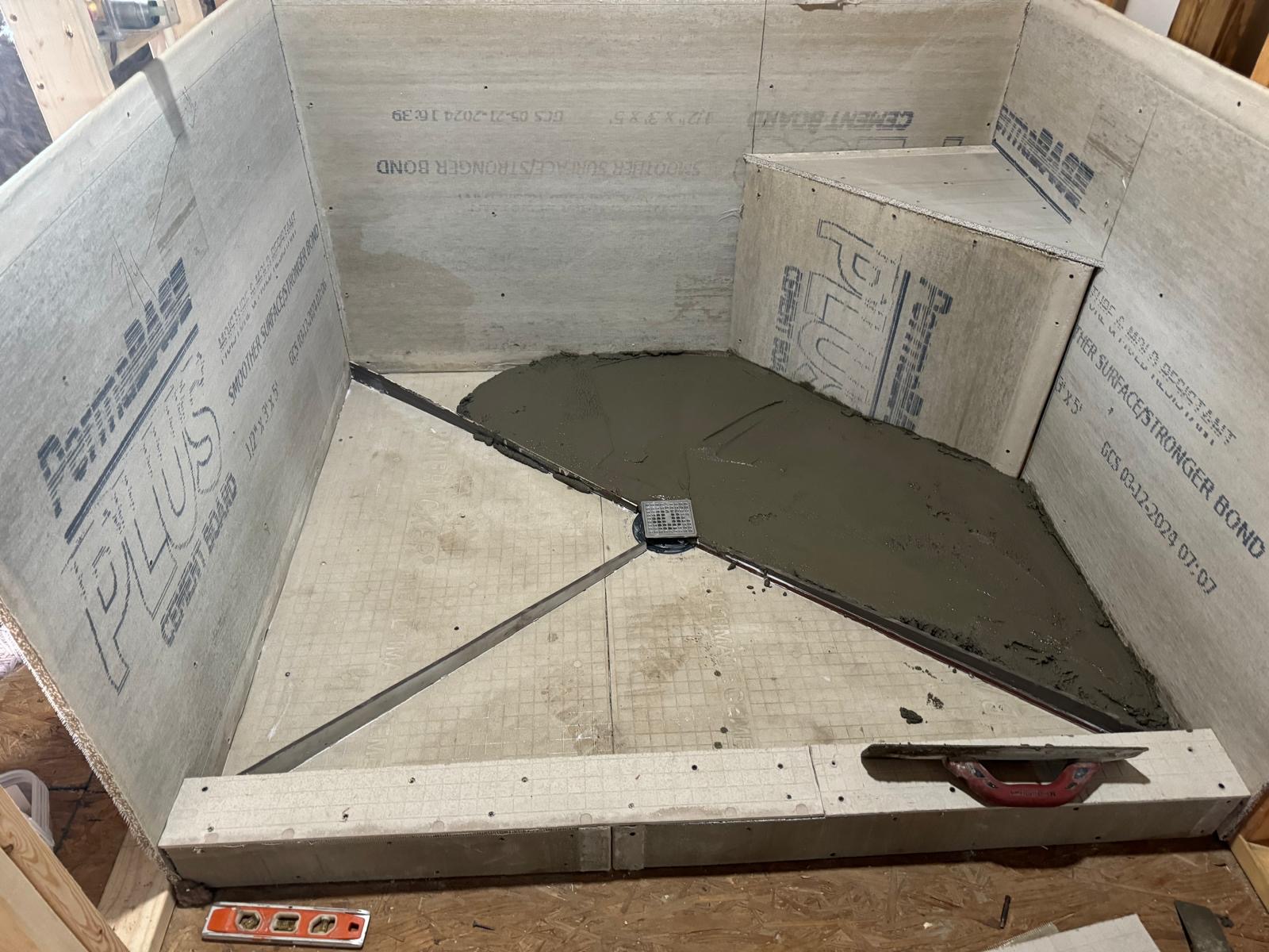 Sloped mortar shower pan being floated around a center drain