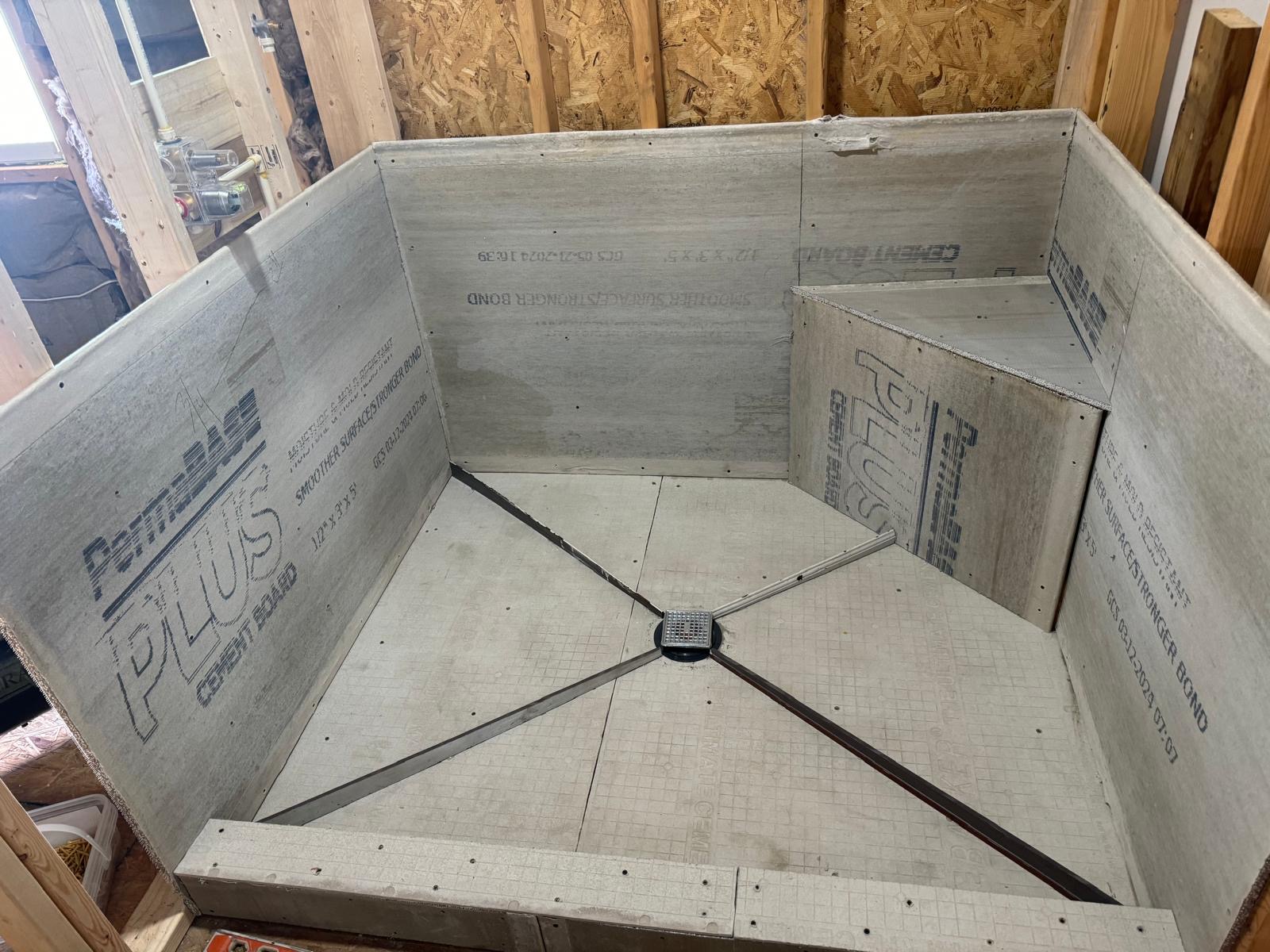 Cement board shower enclosure with bench and linear drain prepared for tile