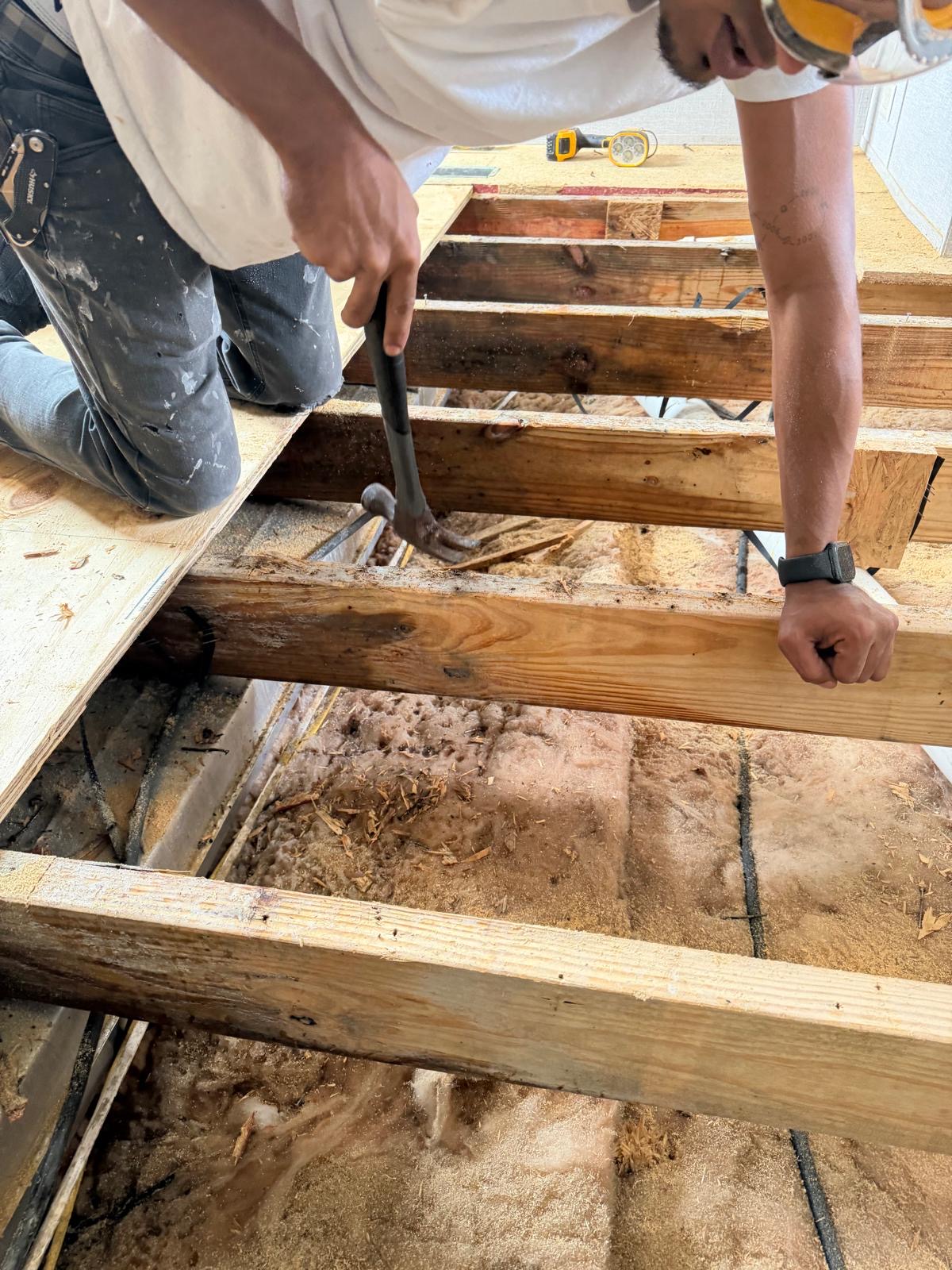 Worker replacing floor joists and subfloor decking during a structural repair