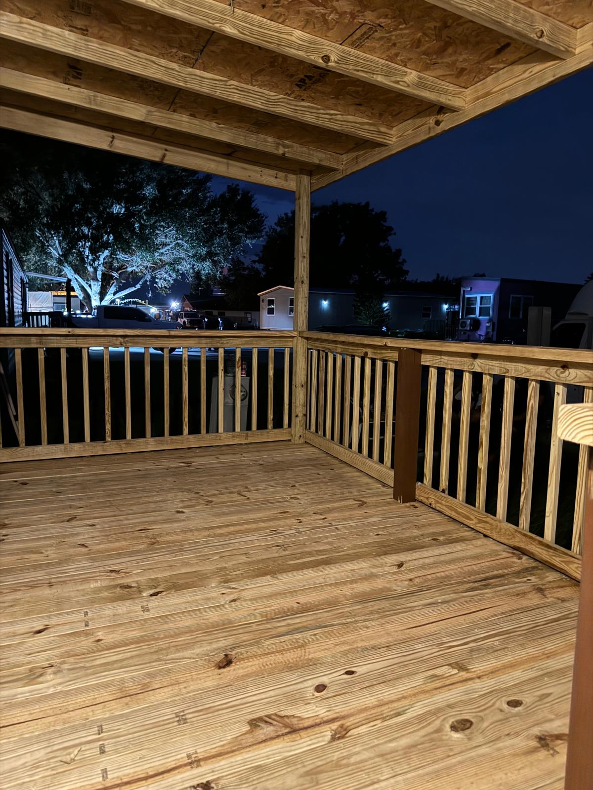 Finished pressure-treated wood deck with railing lit at night