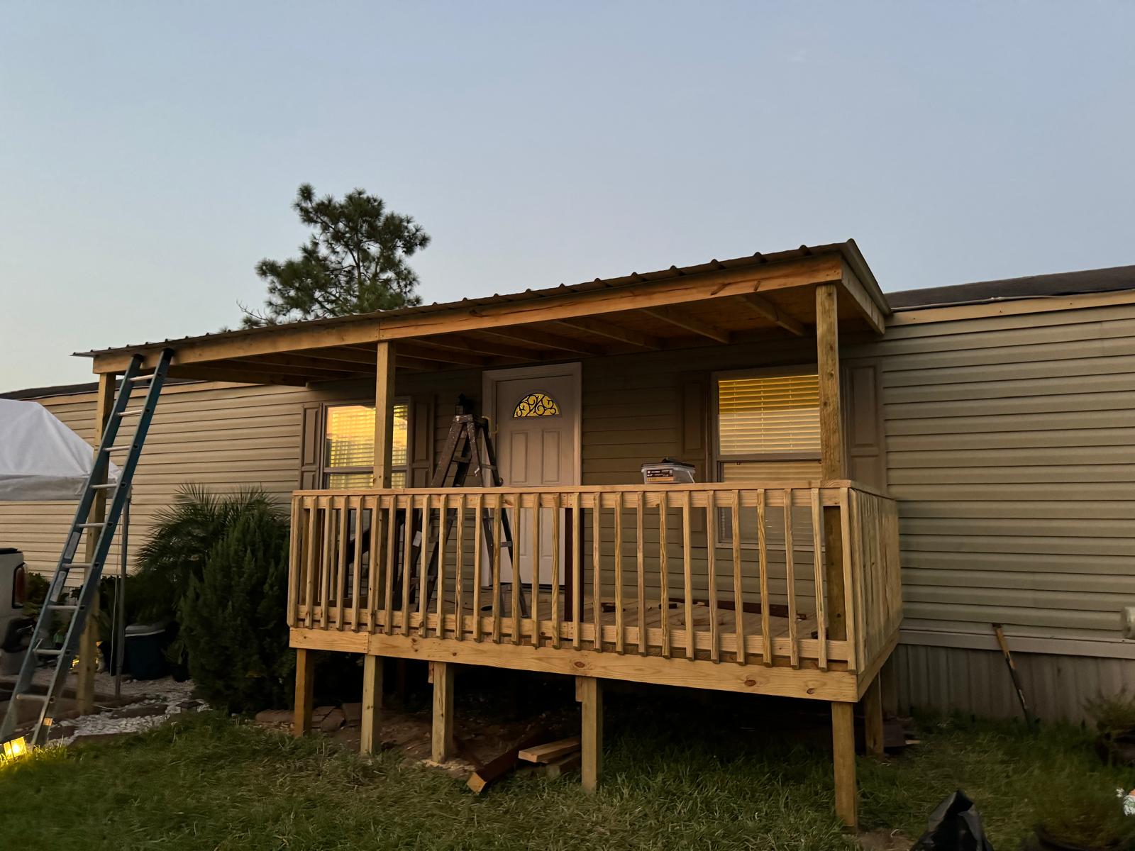 Newly built covered wood porch with railing attached to a manufactured home
