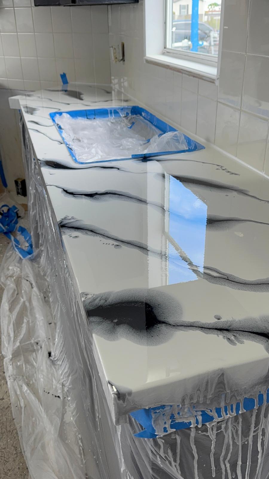 Epoxy resin countertop coating being poured and taped off around a sink cutout