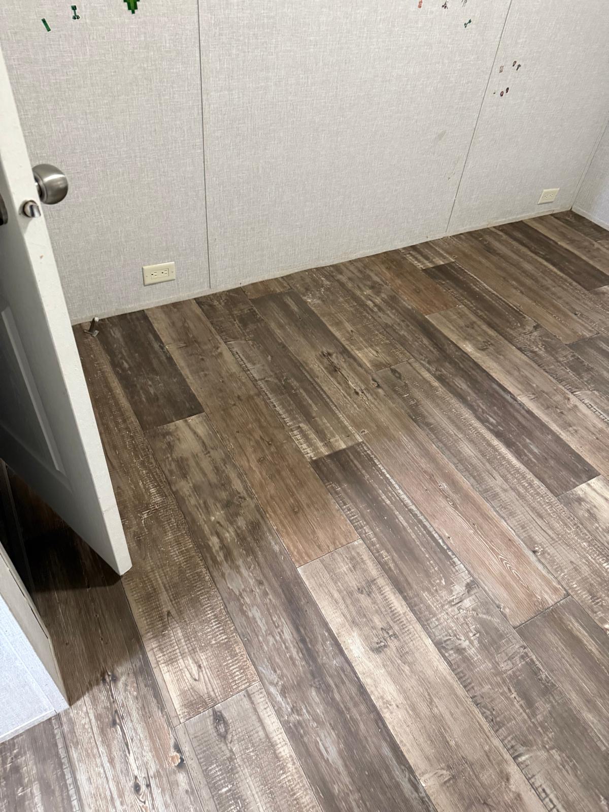Finished rustic gray vinyl plank flooring in a bedroom