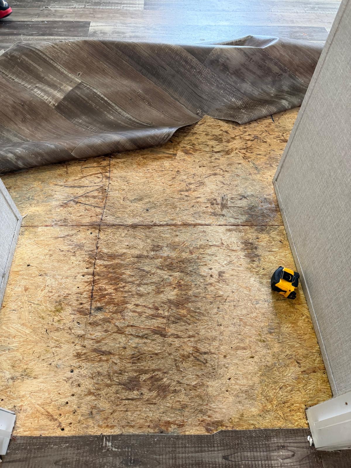 Vinyl plank flooring being installed over subfloor with a tape measure on the deck